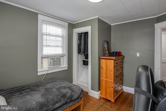 bedroom featuring wood finished floors, ornamental molding, cooling unit, and baseboards