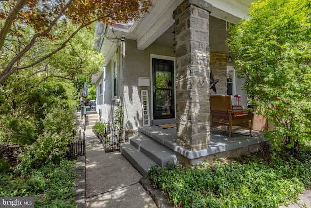 view of property exterior featuring stucco siding, stone siding, and covered porch