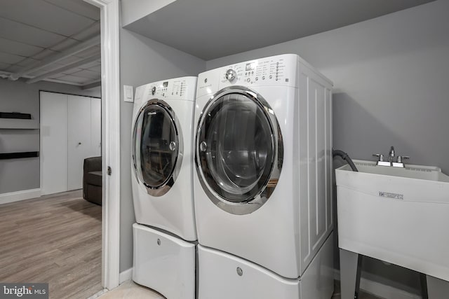 laundry room featuring washing machine and clothes dryer, light wood finished floors, and baseboards