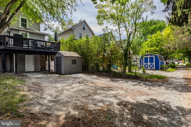 rear view of property featuring a shed, a deck, and an outbuilding
