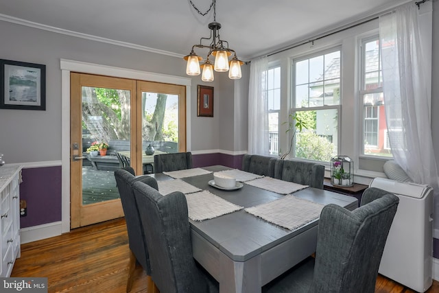 dining space featuring healthy amount of natural light, dark wood-type flooring, a chandelier, and ornamental molding