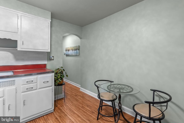 217 Lake Ave, Hamilton, NJ 08610 - kitchen featuring stainless steel countertops, white cabinets, light wood finished floors, arched walkways, and baseboards