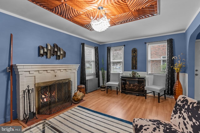 217 Lake Ave, Hamilton, NJ 08610 - living area featuring arched walkways, a brick fireplace, radiator, wood finished floors, and crown molding