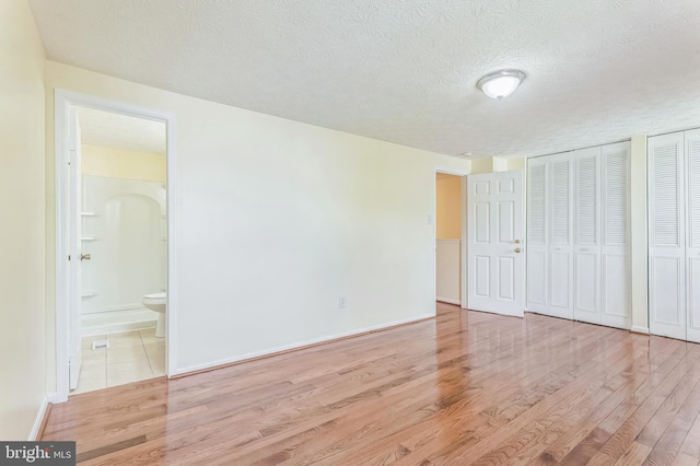 8151 Mandan Ter, Greenbelt, MD 20770 - unfurnished bedroom featuring a textured ceiling, two closets, wood finished floors, ensuite bath, and baseboards