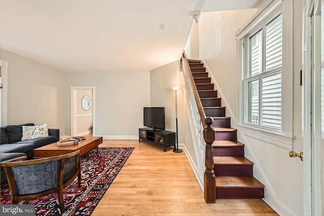 living area featuring stairs, light wood-style floors, and baseboards