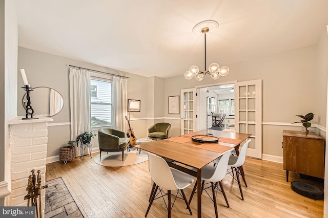 dining room with healthy amount of natural light, light wood finished floors, a chandelier, and baseboards