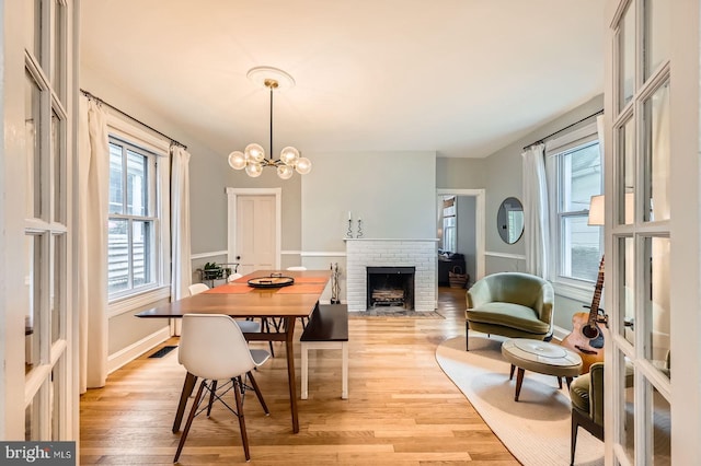 dining room with a fireplace, light wood finished floors, and a chandelier