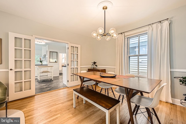 dining area with wood finished floors, french doors, a chandelier, and baseboards