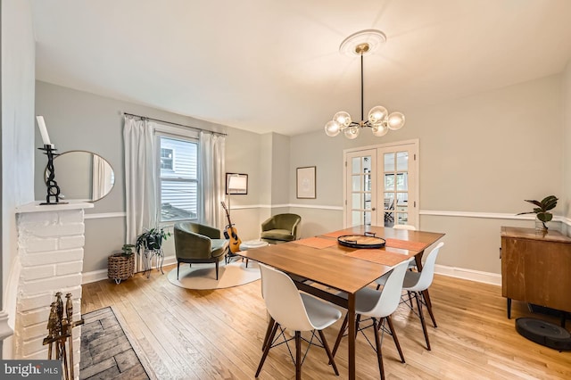 dining space with light wood-style floors, french doors, a chandelier, and baseboards