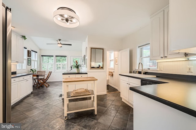 kitchen featuring a sink, plenty of natural light, dark countertops, and baseboards