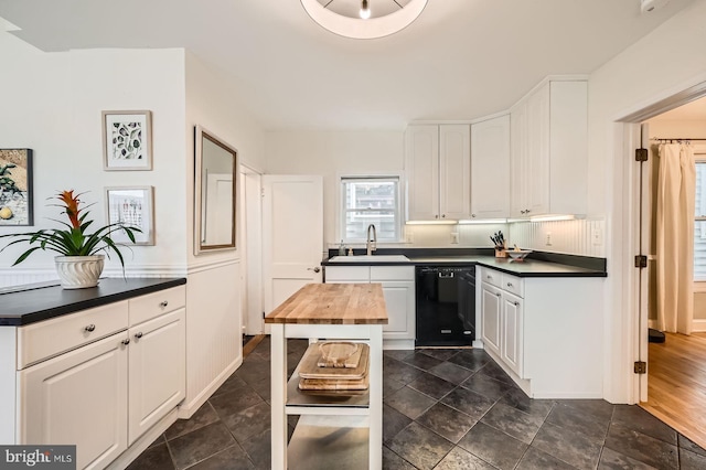 kitchen with black dishwasher, white cabinetry, and a sink