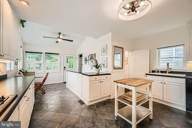kitchen featuring a sink, ceiling fan, dark countertops, lofted ceiling, and white cabinetry