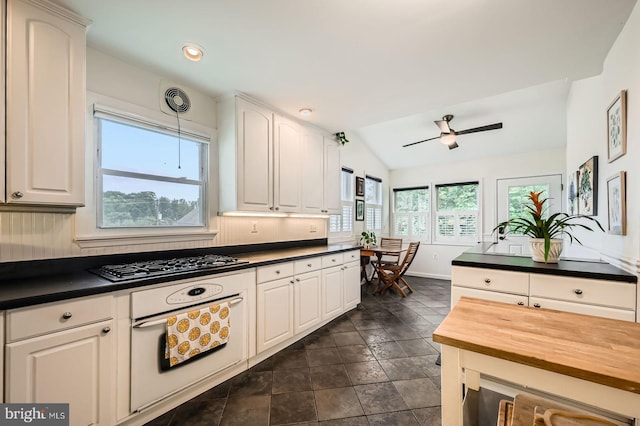 kitchen featuring vaulted ceiling, ceiling fan, gas stovetop, white cabinetry, and butcher block counters