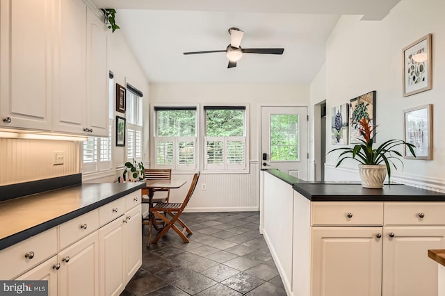 kitchen featuring dark countertops, a ceiling fan, baseboards, and lofted ceiling