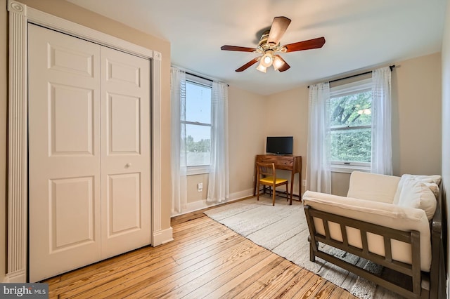 sitting room featuring healthy amount of natural light, light wood-style flooring, a ceiling fan, and baseboards