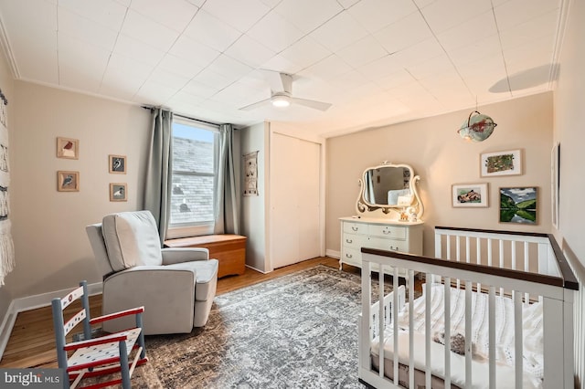 bedroom with wood finished floors, baseboards, and a nursery area