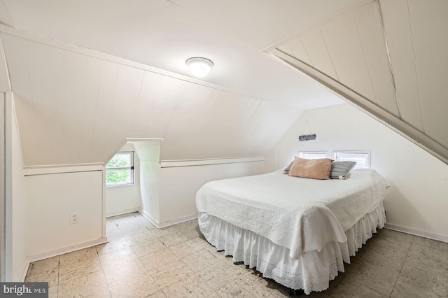 bedroom with vaulted ceiling, light floors, and baseboards