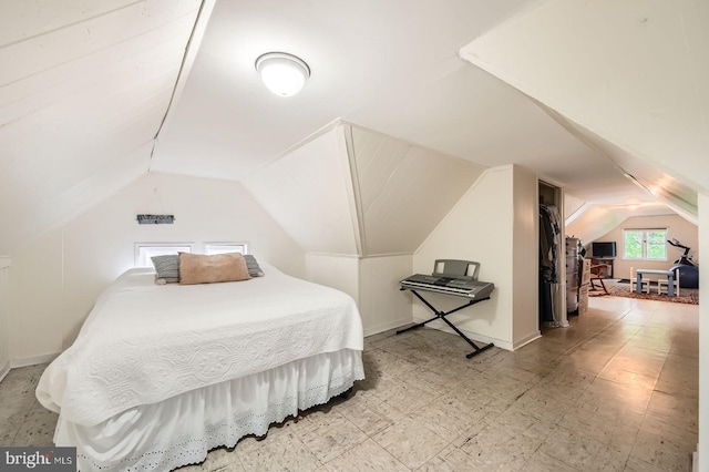 bedroom with lofted ceiling and light floors