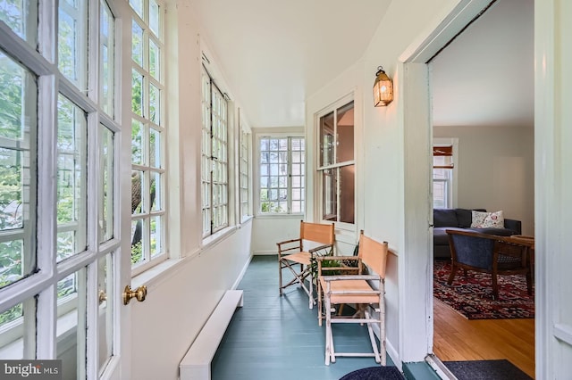 sunroom / solarium with wood finished floors, baseboard heating, and baseboards