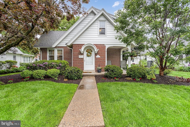 tudor house featuring brick siding, a front yard, and a porch