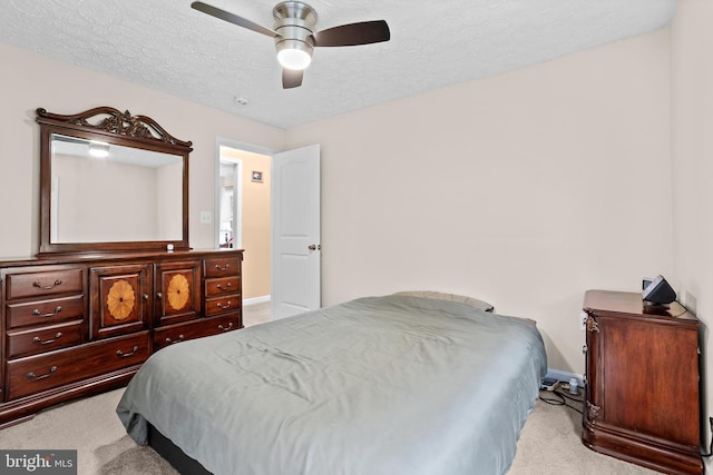 bedroom with light carpet, baseboards, a textured ceiling, and a ceiling fan