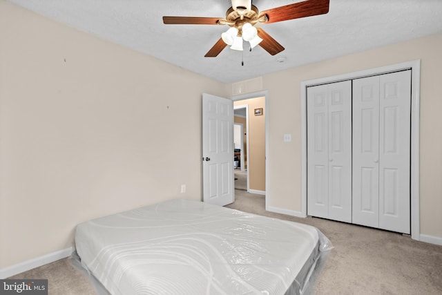 bedroom with light colored carpet, baseboards, ceiling fan, and a closet