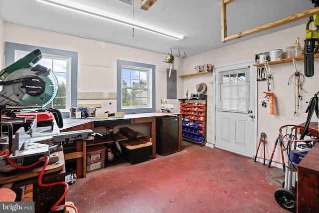misc room featuring a workshop area, healthy amount of natural light, electric panel, and concrete flooring