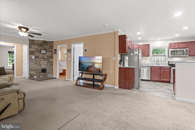 living room with ornamental molding, light carpet, healthy amount of natural light, a ceiling fan, and baseboards