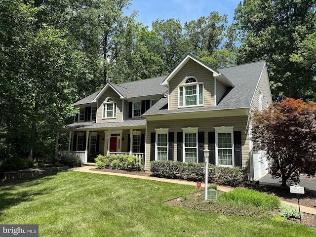 colonial-style house featuring a porch, a front lawn, and a shingled roof