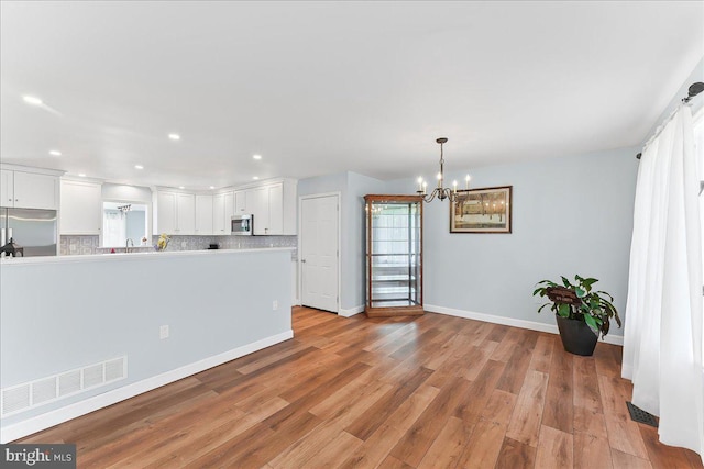 kitchen featuring appliances with stainless steel finishes, a chandelier, white cabinets, light countertops, and decorative backsplash