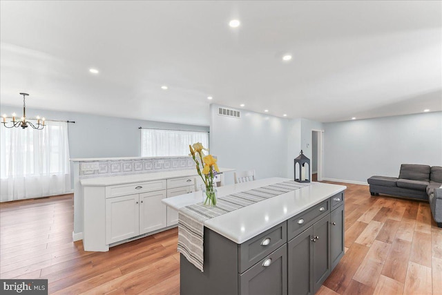 kitchen featuring a kitchen island, open floor plan, gray cabinetry, a chandelier, and light wood-style floors