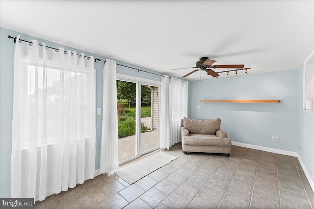 living area featuring a ceiling fan, rail lighting, and baseboards