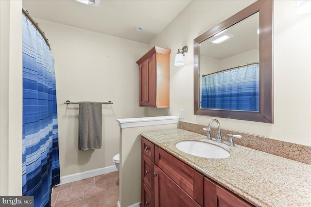bathroom with toilet, vanity, baseboards, and tile patterned flooring