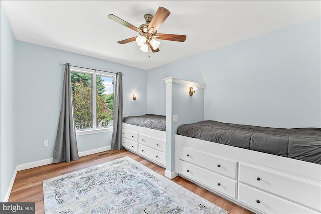 bedroom with light wood finished floors, baseboards, and a ceiling fan