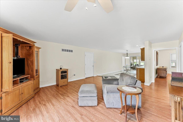 living room featuring light wood-type flooring, ceiling fan, and baseboards