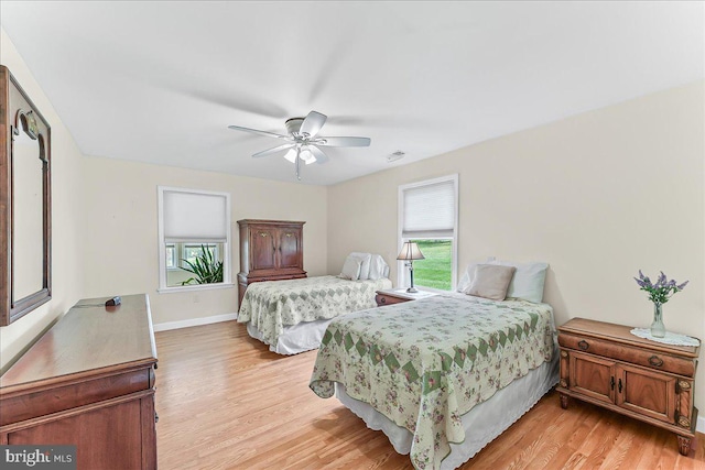 bedroom with light wood finished floors, a ceiling fan, and baseboards