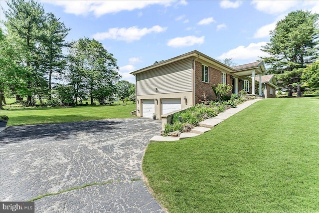 view of property exterior featuring a garage, driveway, brick siding, and a yard