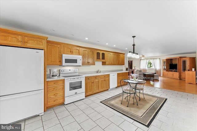 kitchen featuring white appliances, light countertops, a chandelier, a sink, and decorative light fixtures