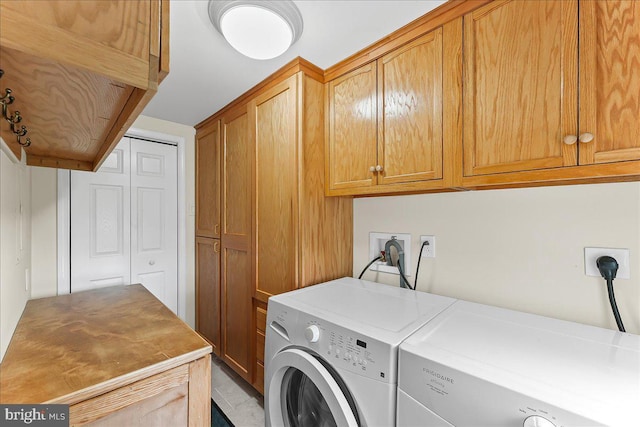 clothes washing area featuring washing machine and clothes dryer and cabinet space
