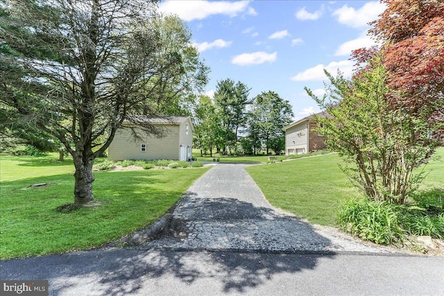 view of community with a yard and asphalt driveway
