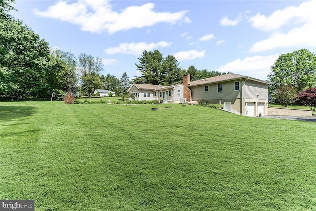 view of green lawn with an attached garage and driveway