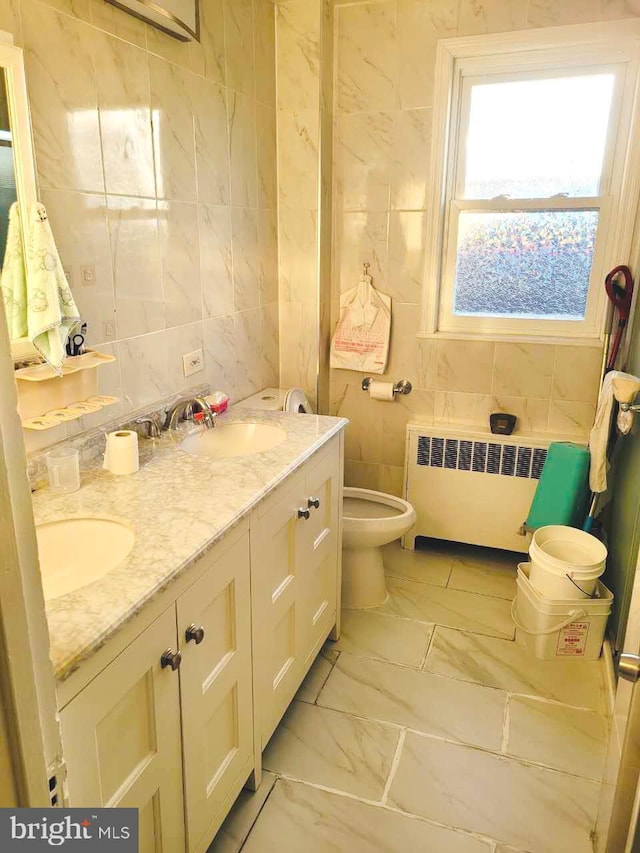 bathroom featuring radiator heating unit, tile walls, marble look tile flooring, and double vanity