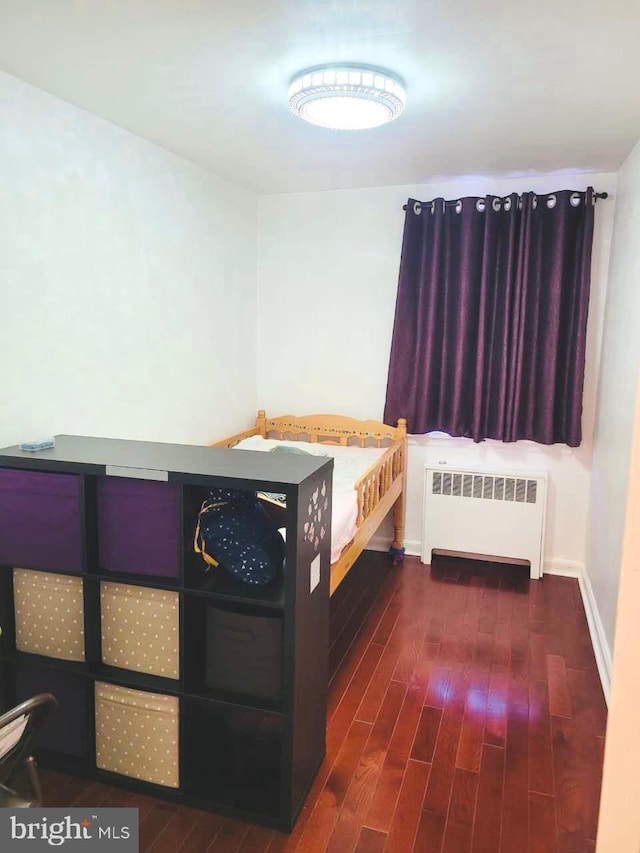 bedroom with radiator heating unit, dark wood finished floors, and baseboards