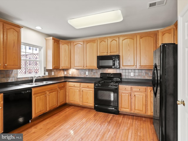 9757 Cheshire Ridge Cir, Manassas, VA 20110 - kitchen featuring black appliances, a sink, dark countertops, light wood-style flooring, and backsplash