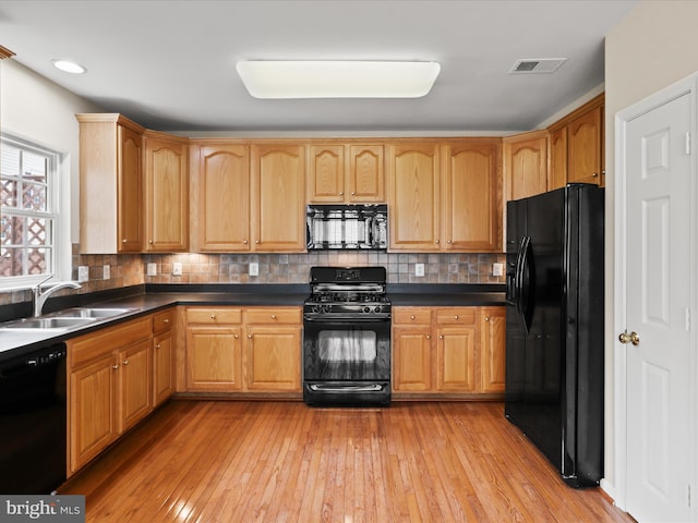 9757 Cheshire Ridge Cir, Manassas, VA 20110 - kitchen featuring black appliances, dark countertops, light wood-style flooring, and backsplash