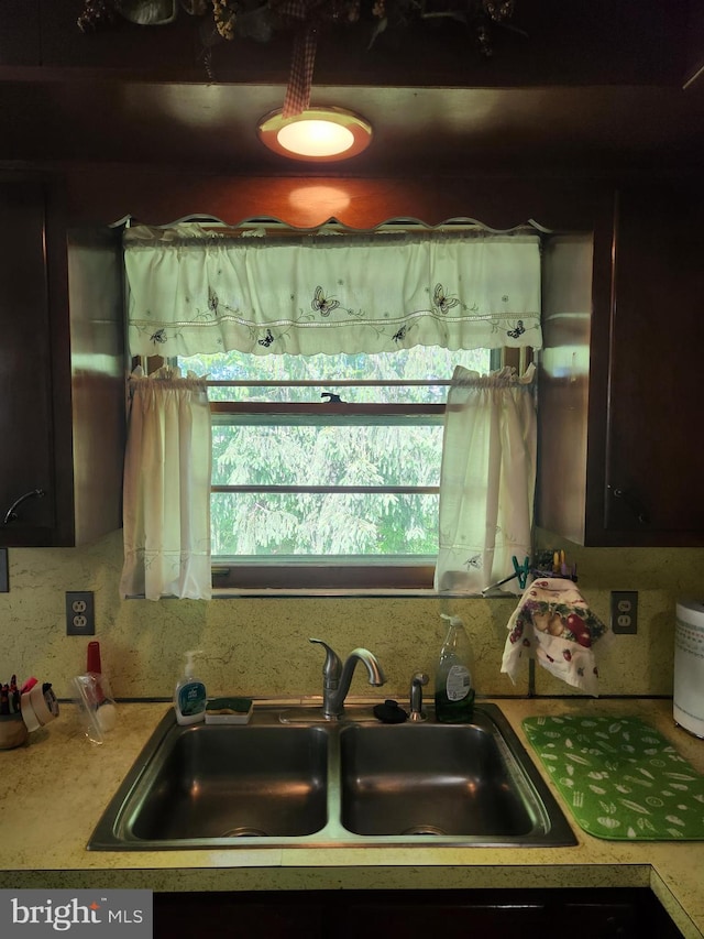 kitchen view of a sink, light countertops, and backsplash