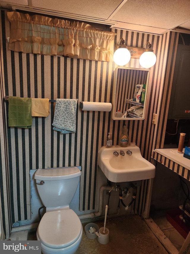 bathroom featuring wallpapered walls, toilet, and a sink