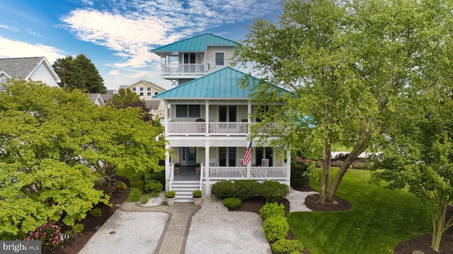 view of front of property featuring a porch, a balcony, a standing seam roof, and metal roof