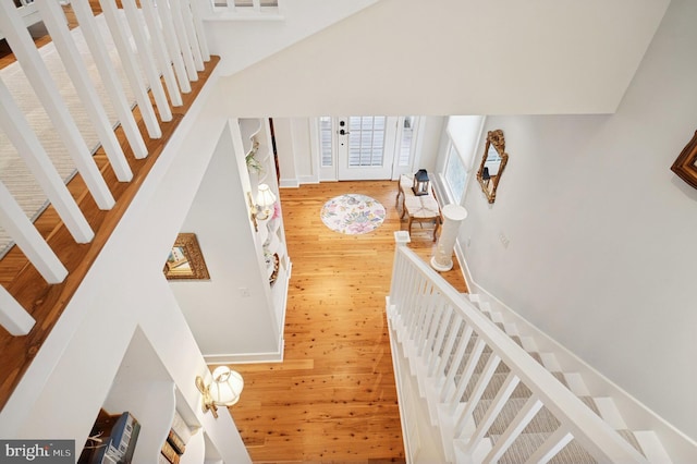 stairway featuring wood finished floors and a towering ceiling