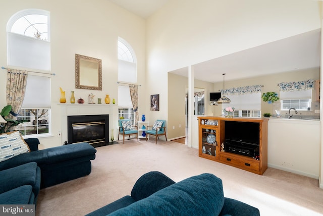 living area featuring carpet flooring, a towering ceiling, a fireplace with flush hearth, and baseboards